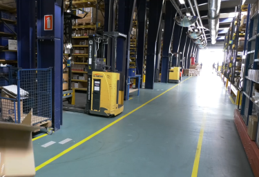 Gang i lagerhal med dagslys for enden